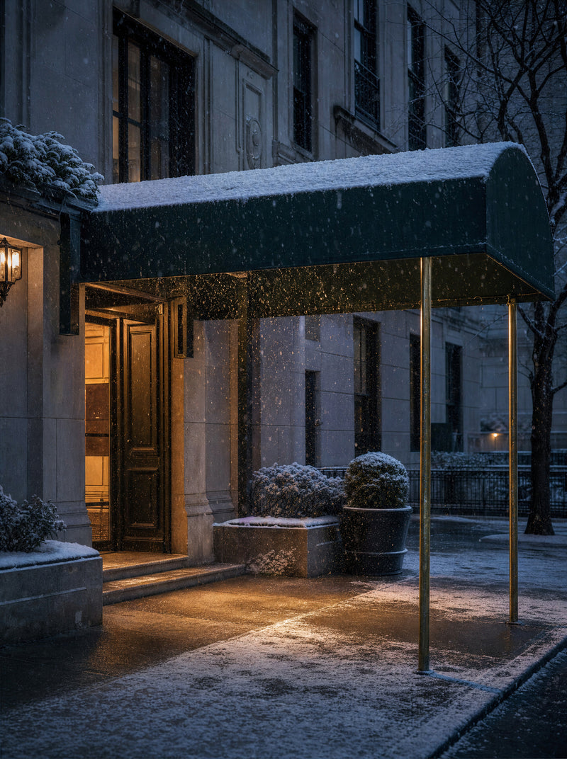 A blank awning over a lit doorway in falling snow, open space lower left