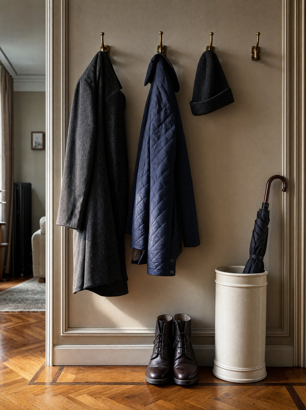Overcoats and jackets on entry hooks beside an umbrella stand on a parquet floor